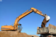 Photo of excavator dumping dirt into the back of a dump truck